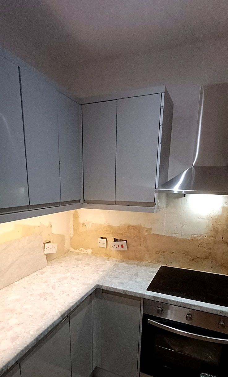 A grey handleless kitchen with marble-effect worktop, fitted, before the splashback went on